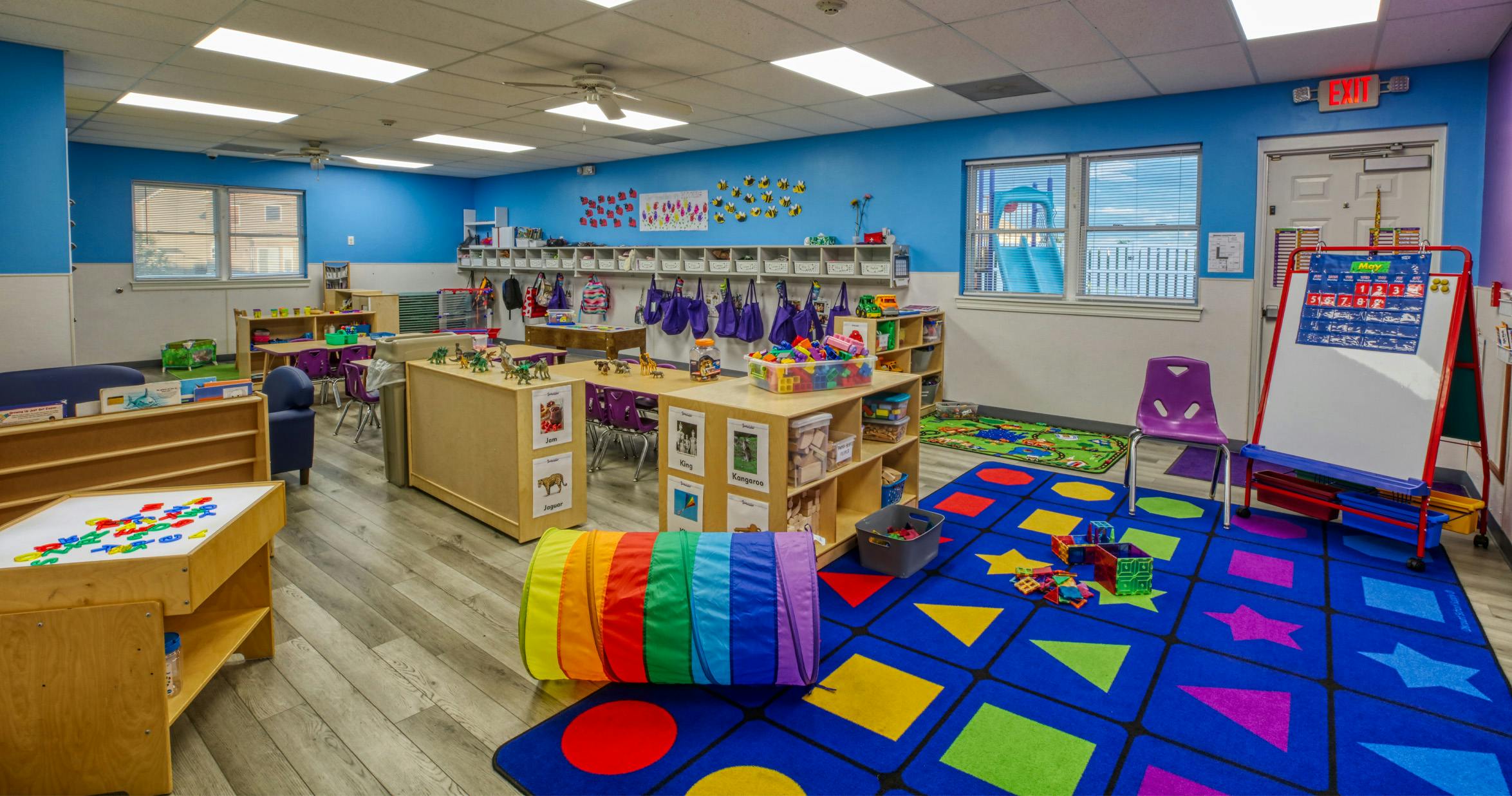 An empty early childhood classroom with colorful carpets and toys