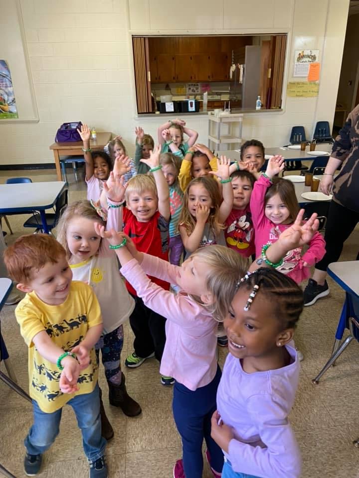 Group of children raising their hands in a classroom