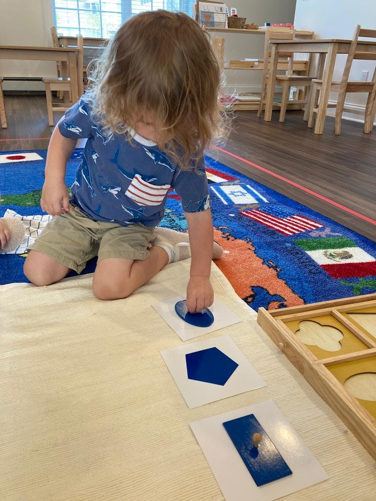 Child playing with blue shape puzzles on a rug