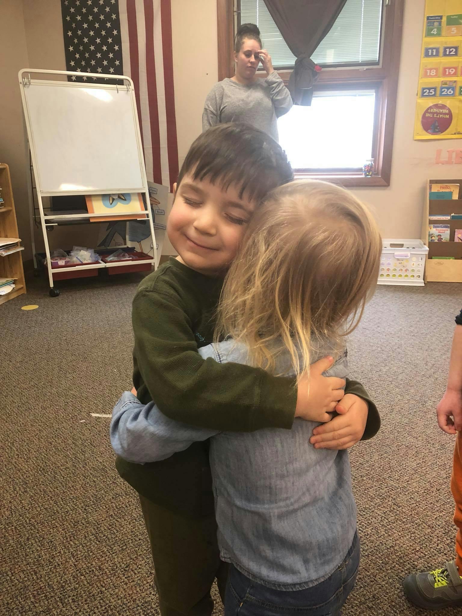 Two children hugging in a classroom