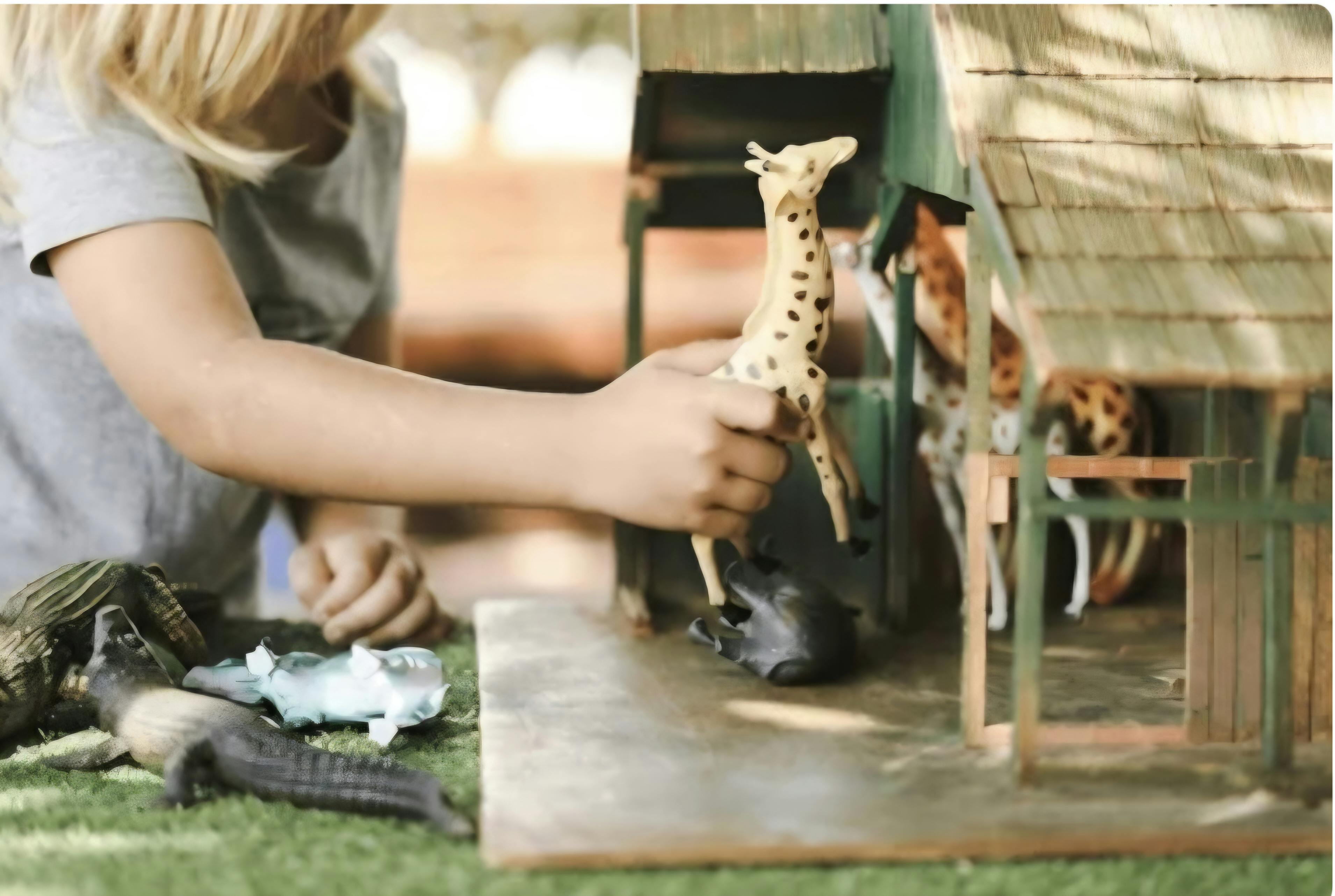 Child playing with a giraffe toy and a dollhouse