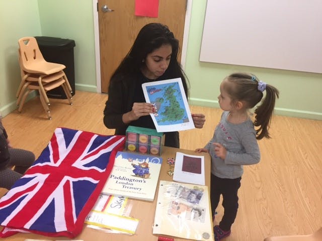 Person holding a map and a child looking at it in a classroom