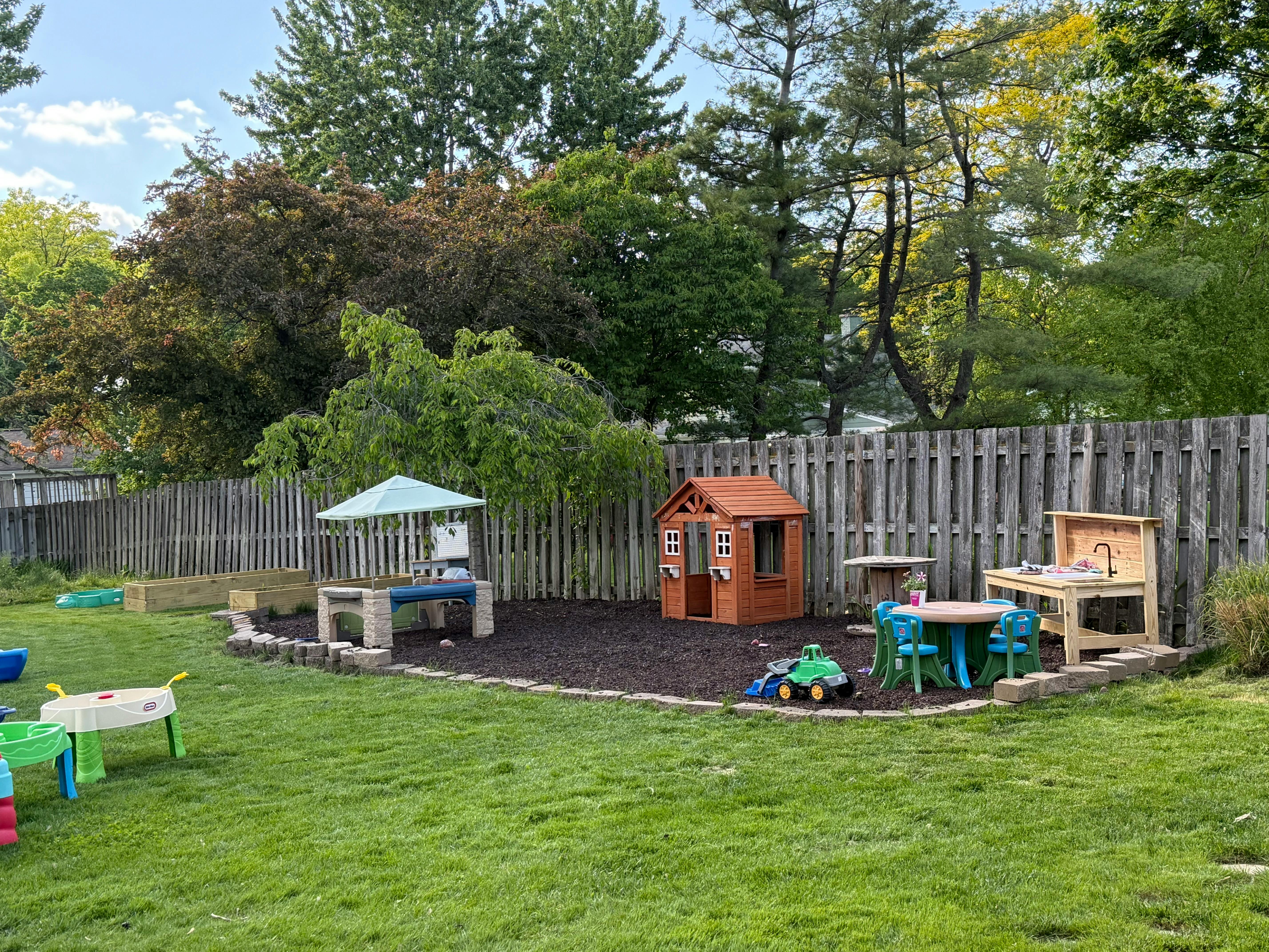 Outdoor play area with a playhouse, tables, and toys