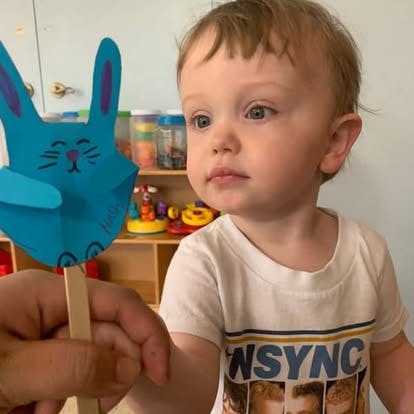 Child looking at a blue paper bunny puppet