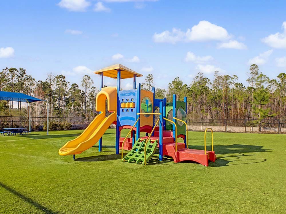 Colorful playground with a yellow slide on green artificial turf