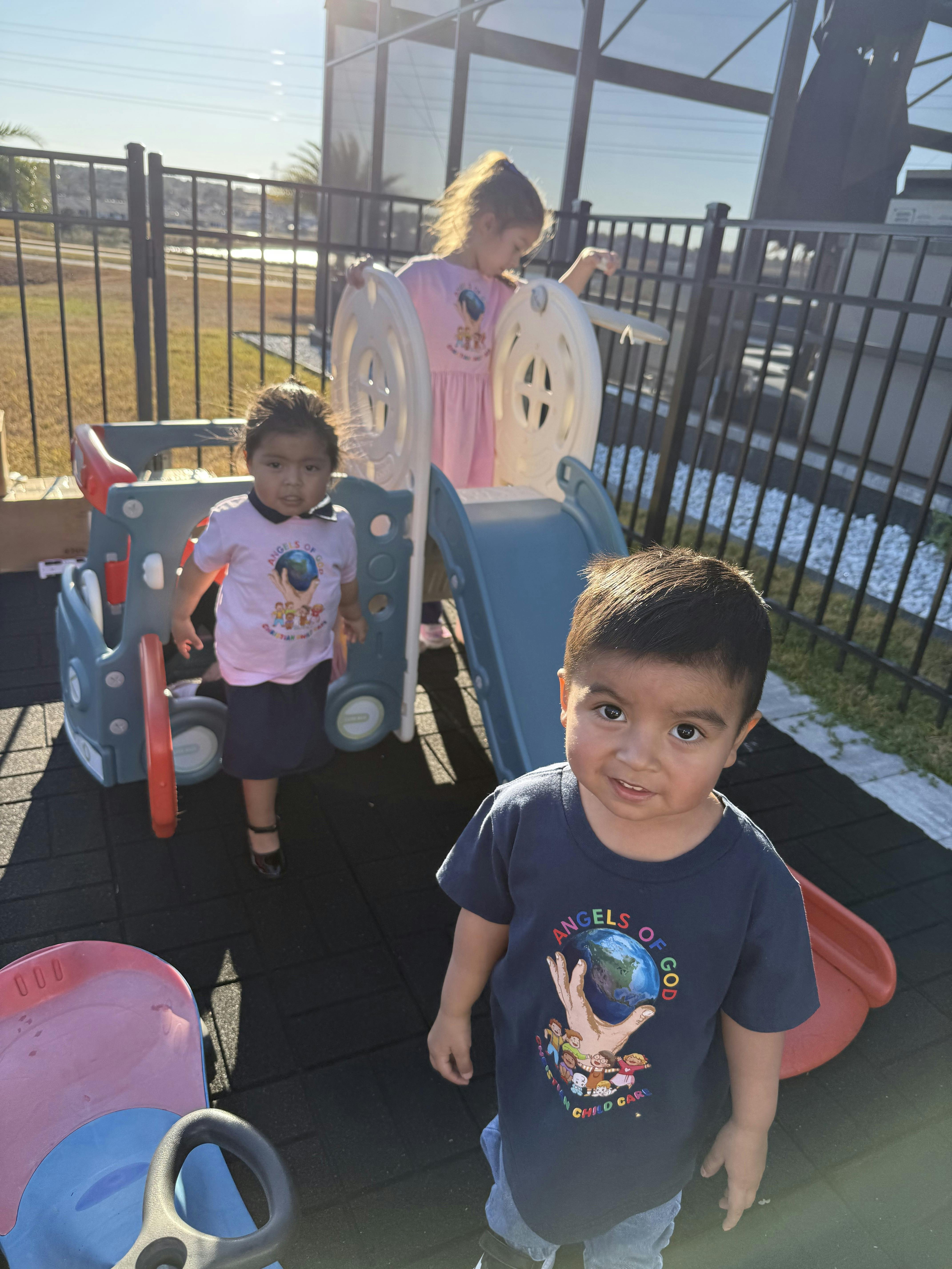 Three children playing on a slide at a playground