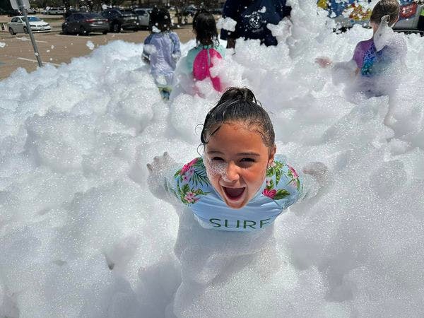 Child in a foam pit with other children in the background