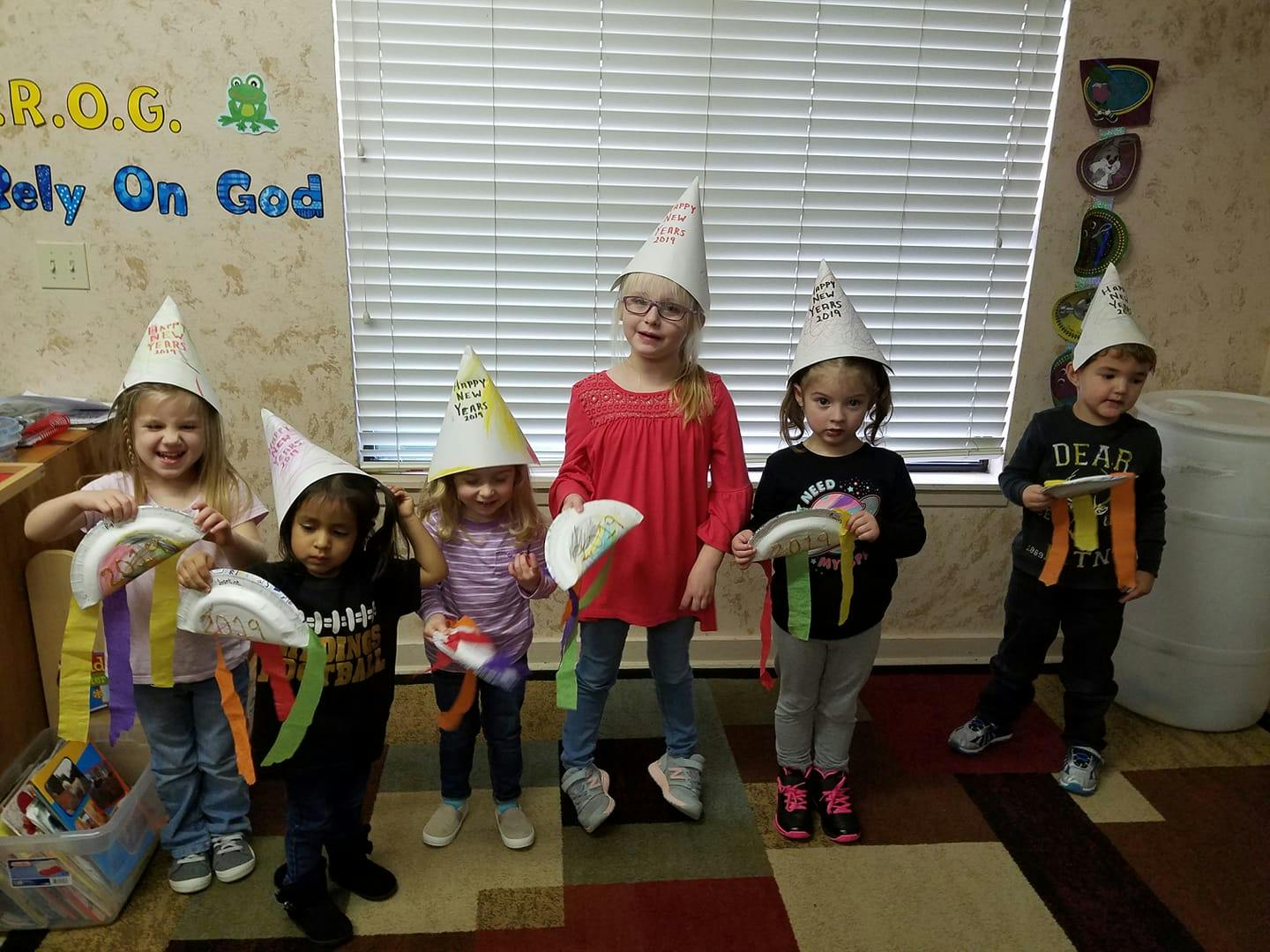 Five children wearing party hats and holding crafts