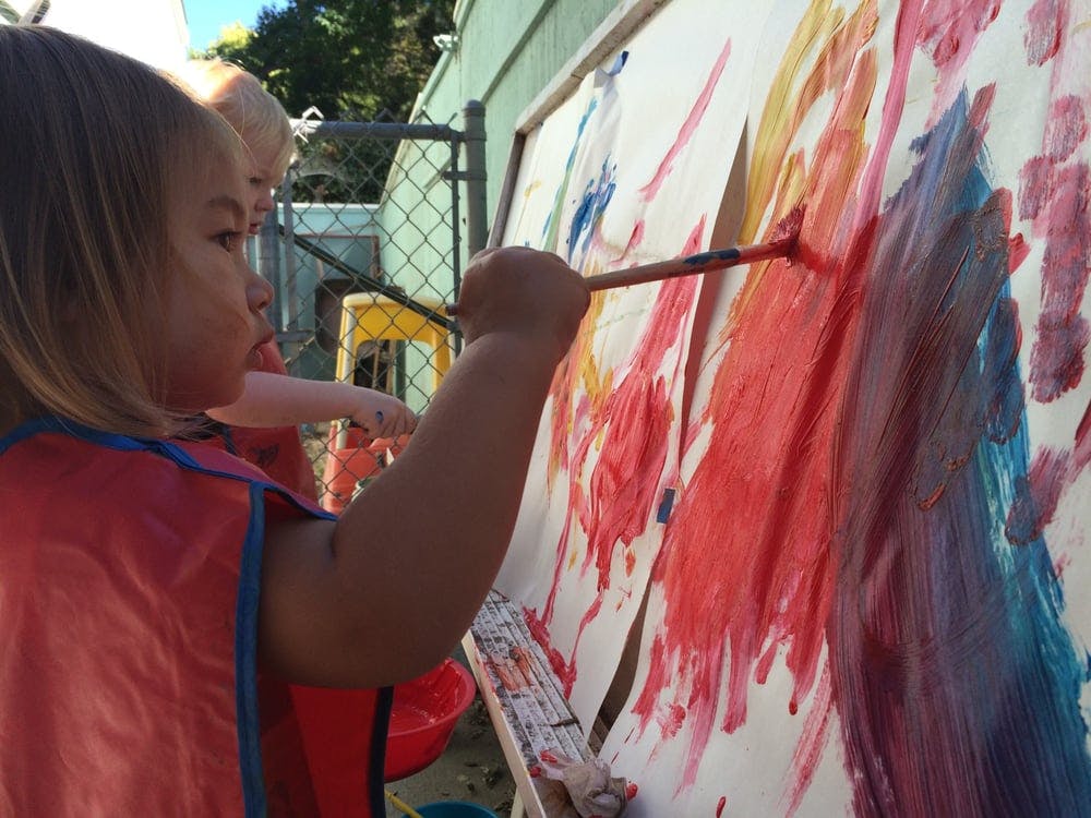 Child painting on a large canvas with a paintbrush