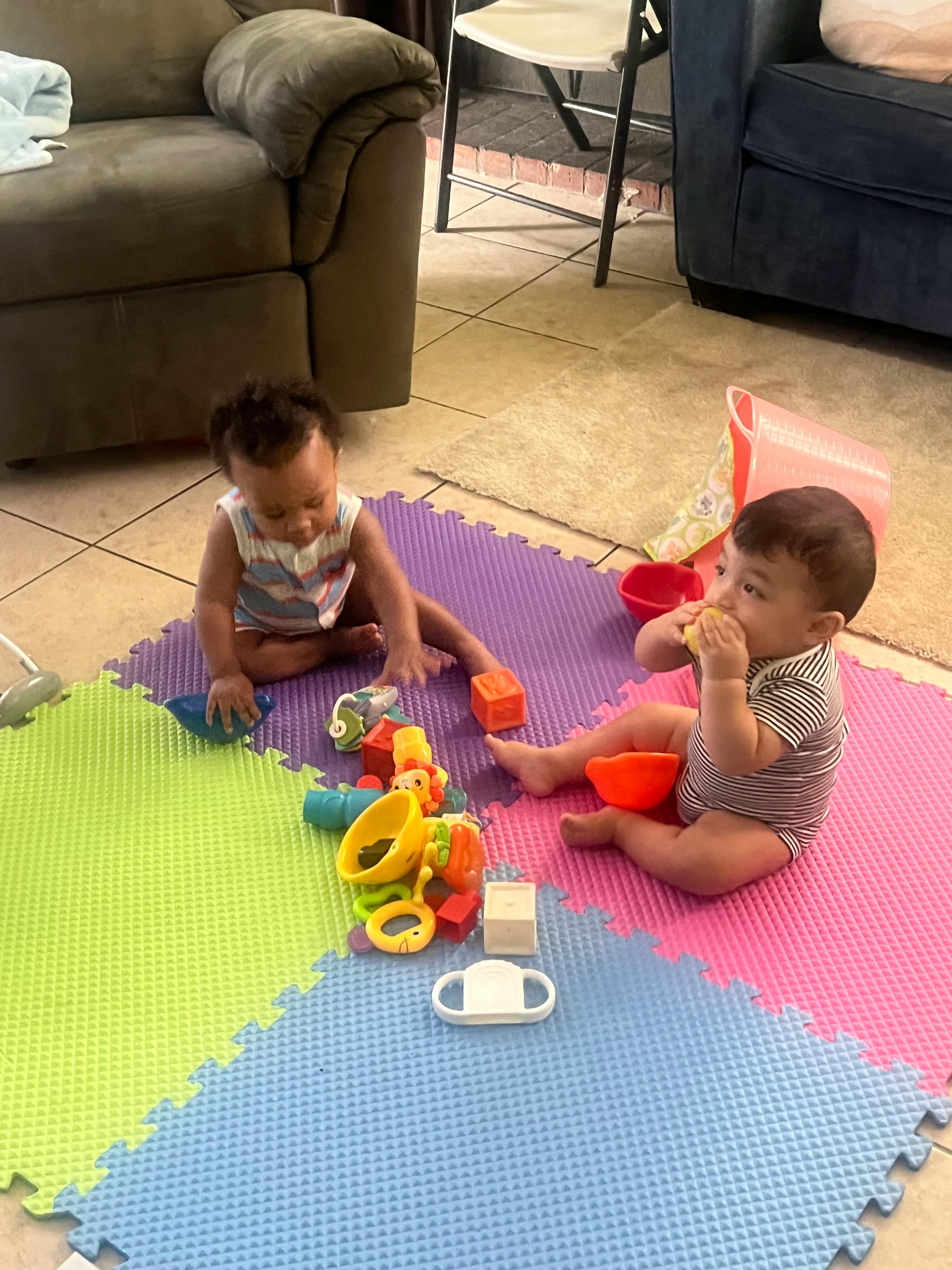 Two children playing with toys on a colorful mat