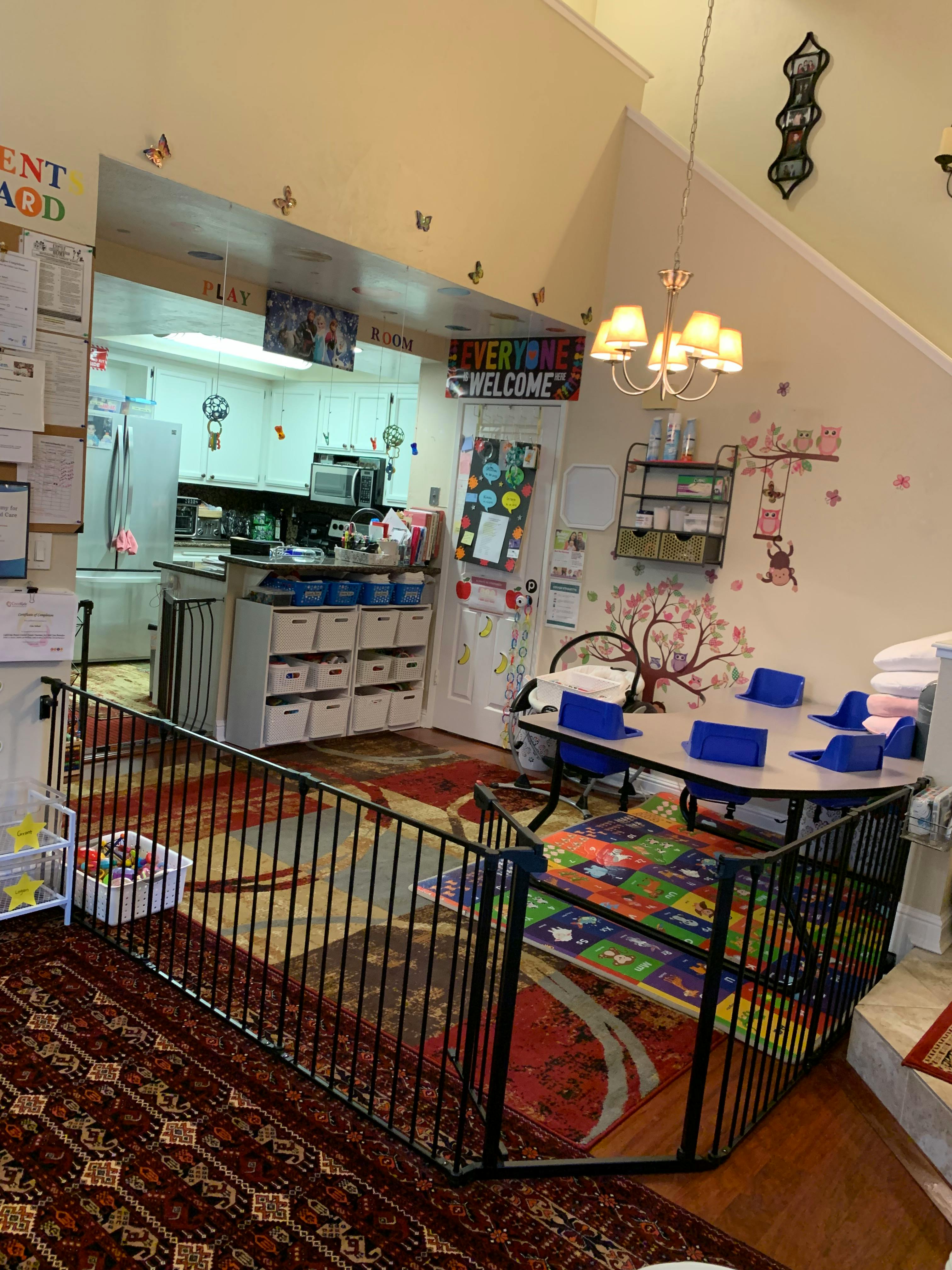 Play area with a gate, small table and chairs, and a kitchen in the background