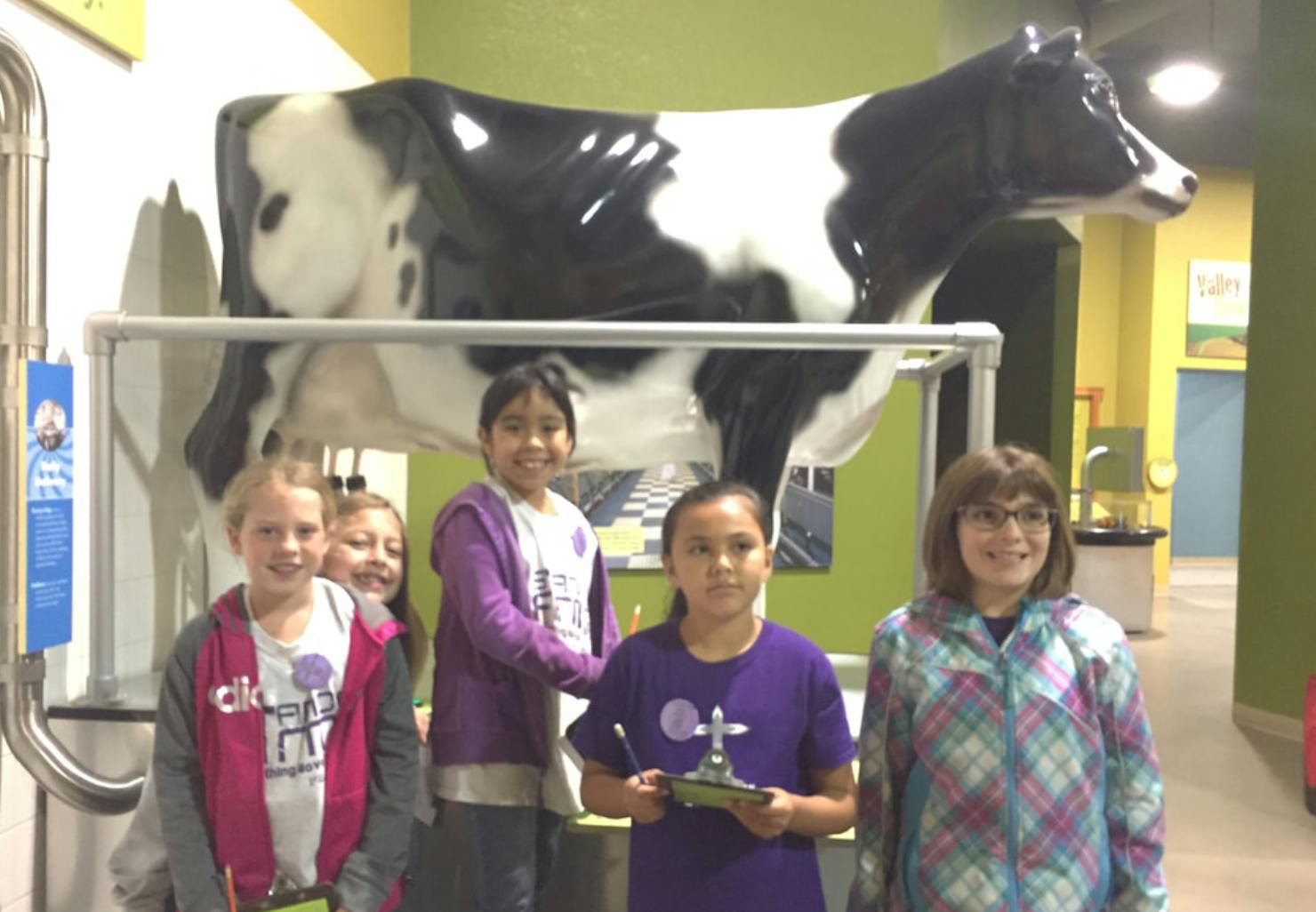 Five children standing in front of a large cow statue