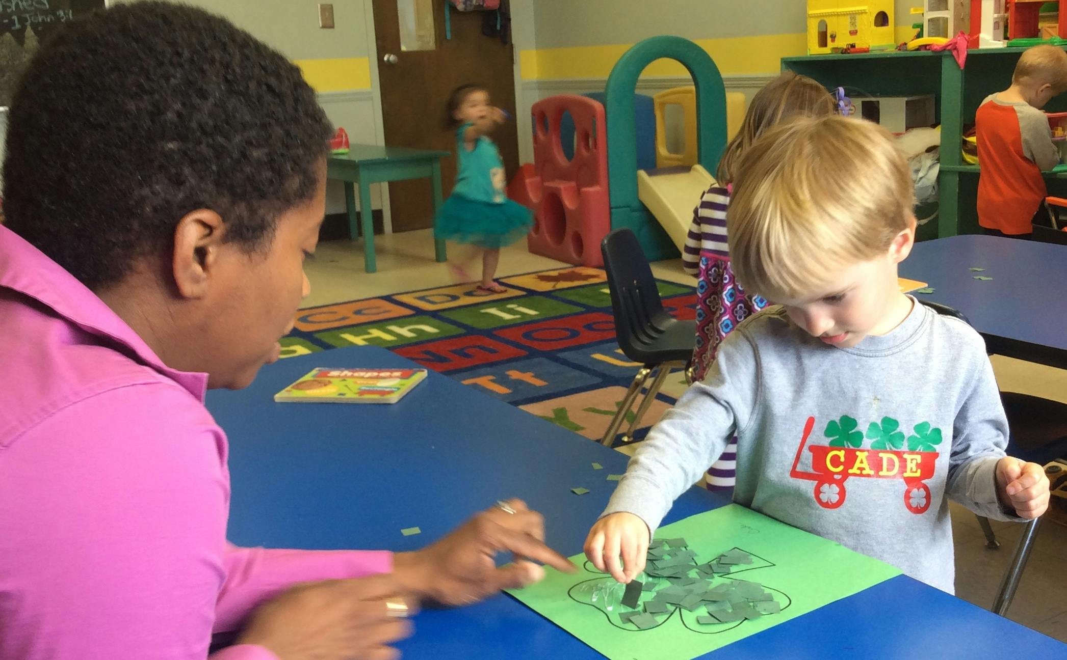 Adult and child at a table working on a craft in a classroom