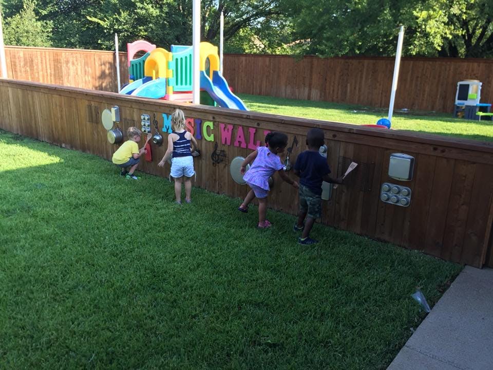 Children playing at a music wall in a backyard