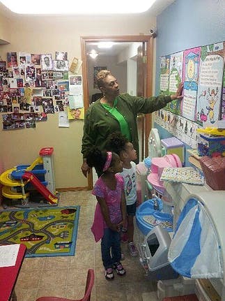 Adult pointing at a chart with two children looking on