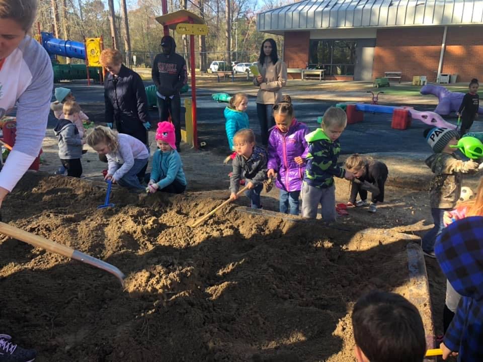 Adults and children playing in a large sandbox