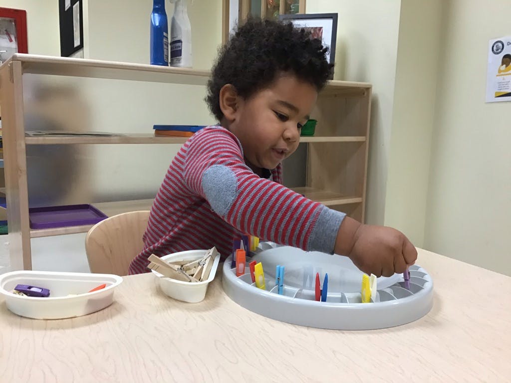 Child playing with colorful pegs and a pegboard in a classroom