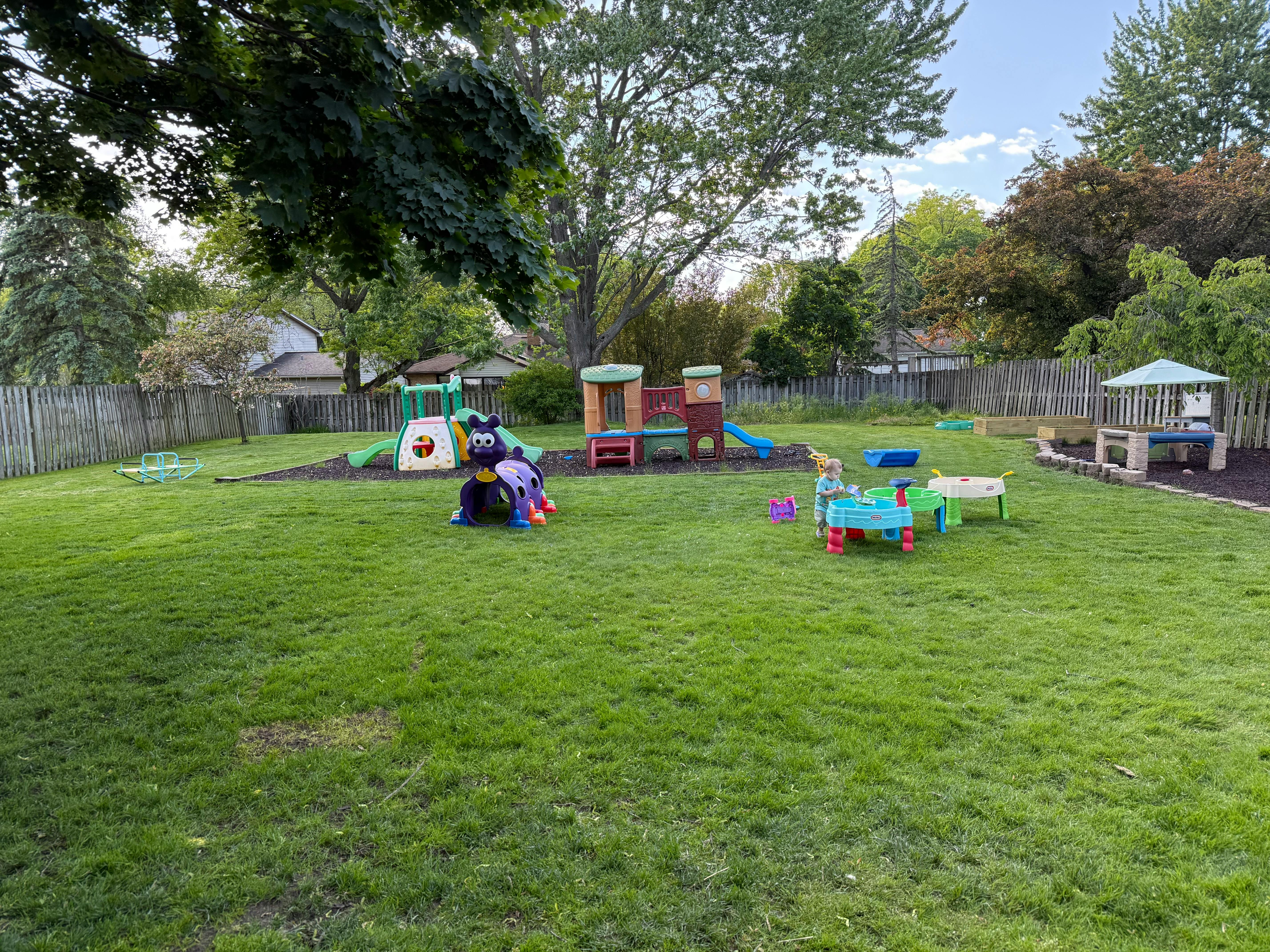 Outdoor playground with various play structures and toys on grass