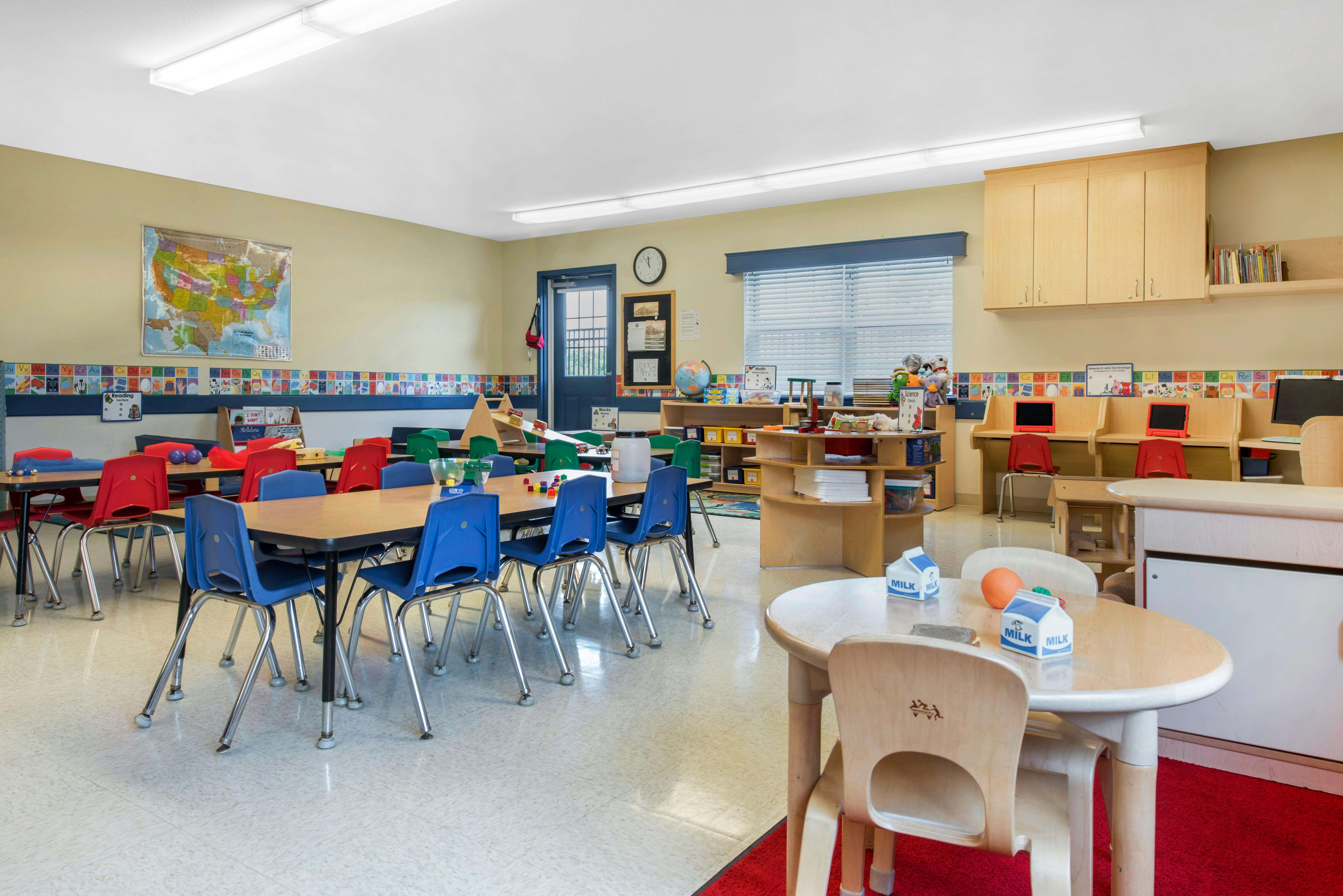 Classroom with tables and chairs for children, alphabet border on wall