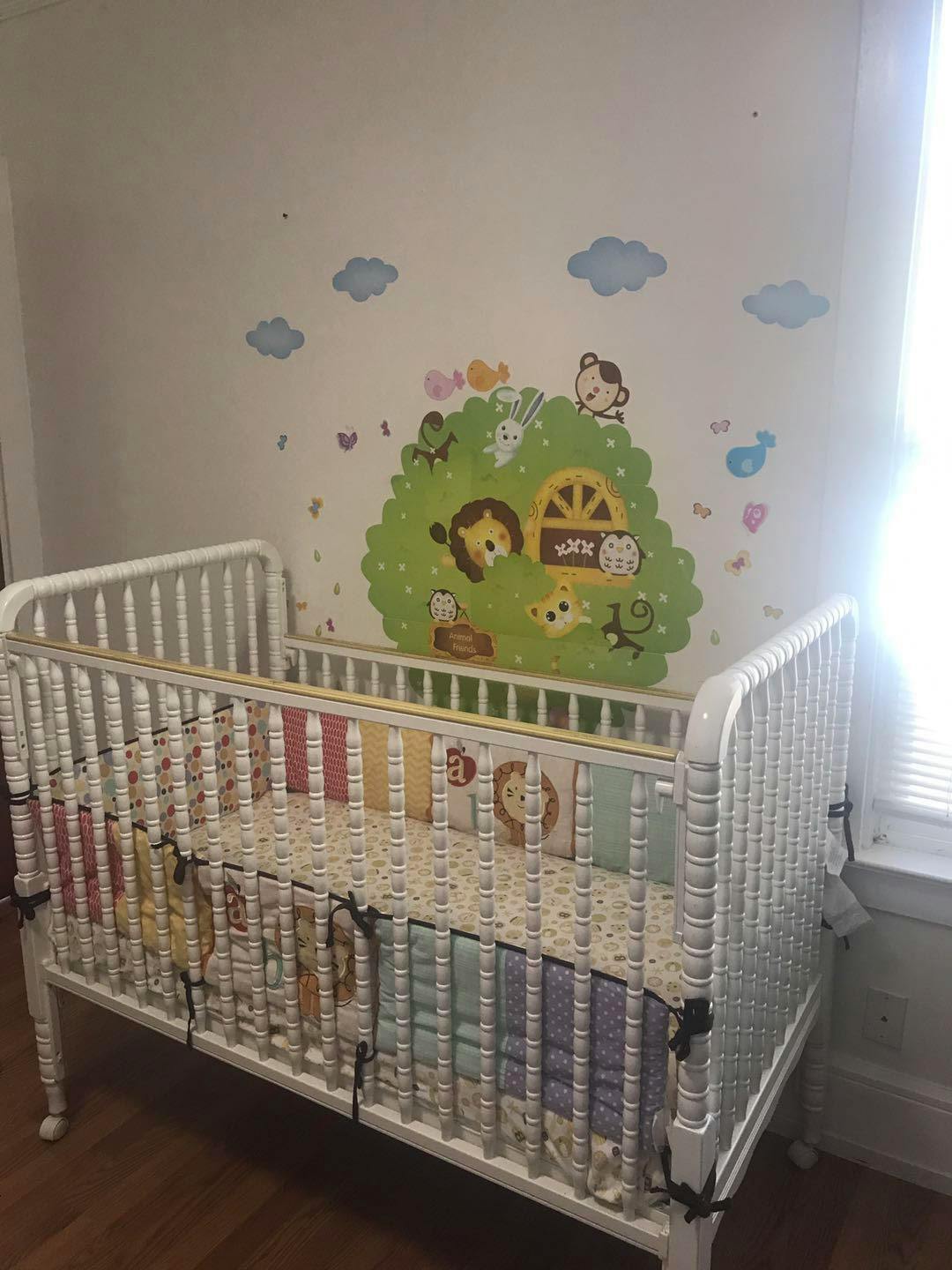 White crib with colorful bedding and animal wall decals