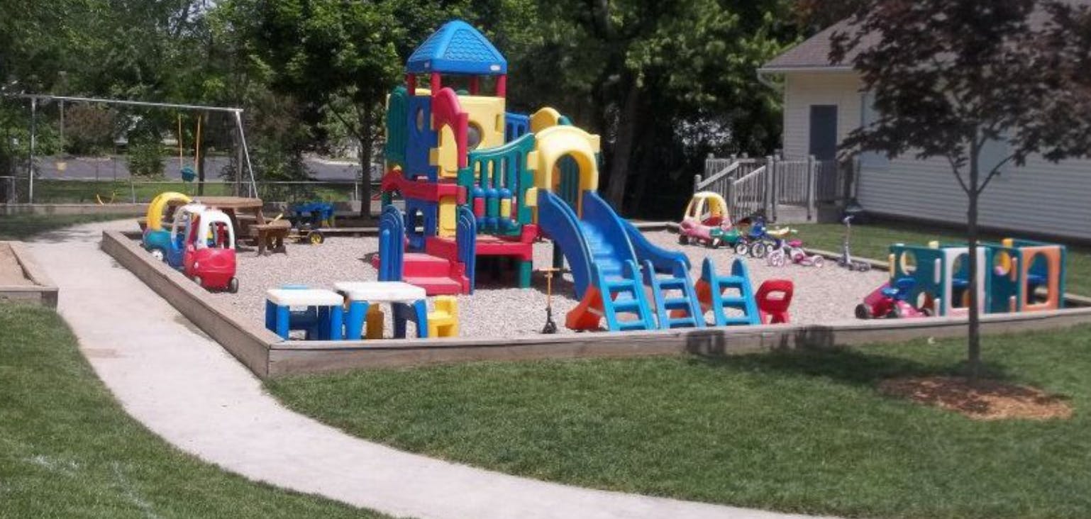 Outdoor playground with colorful play structure, slides, and swings