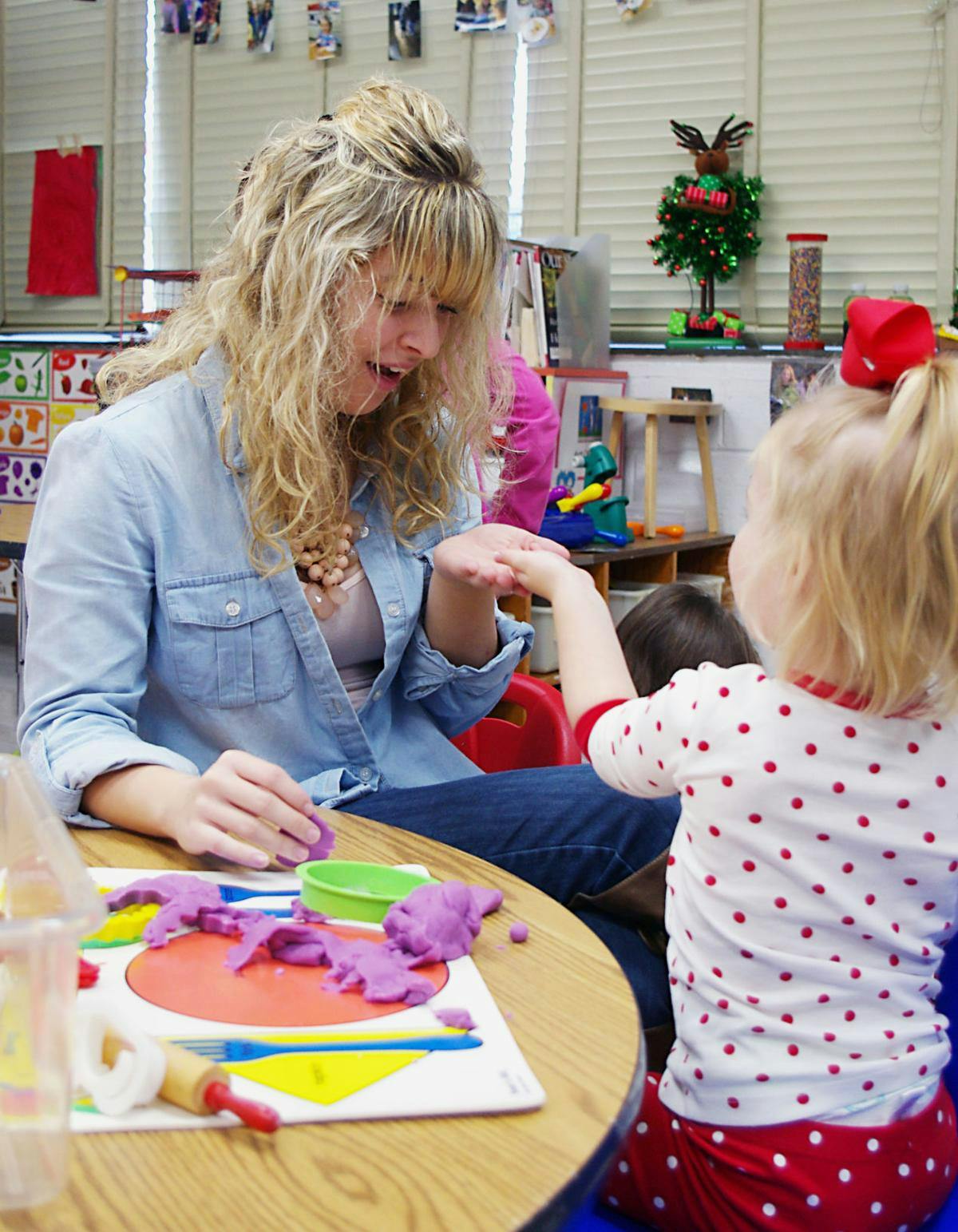 Person and child playing with purple playdough at a table