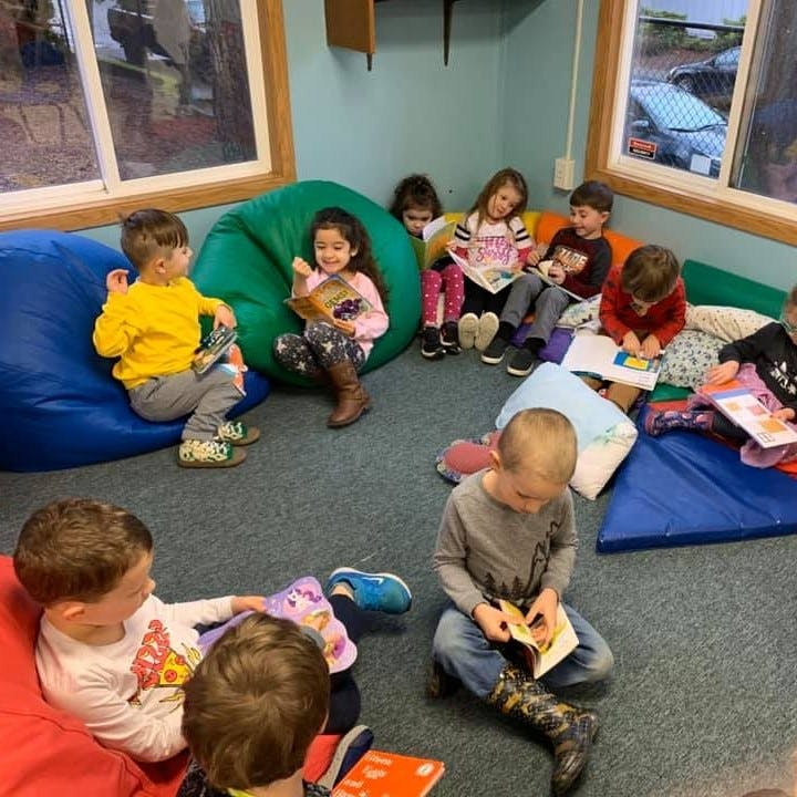 Children sitting on beanbags and floor reading books in a classroom