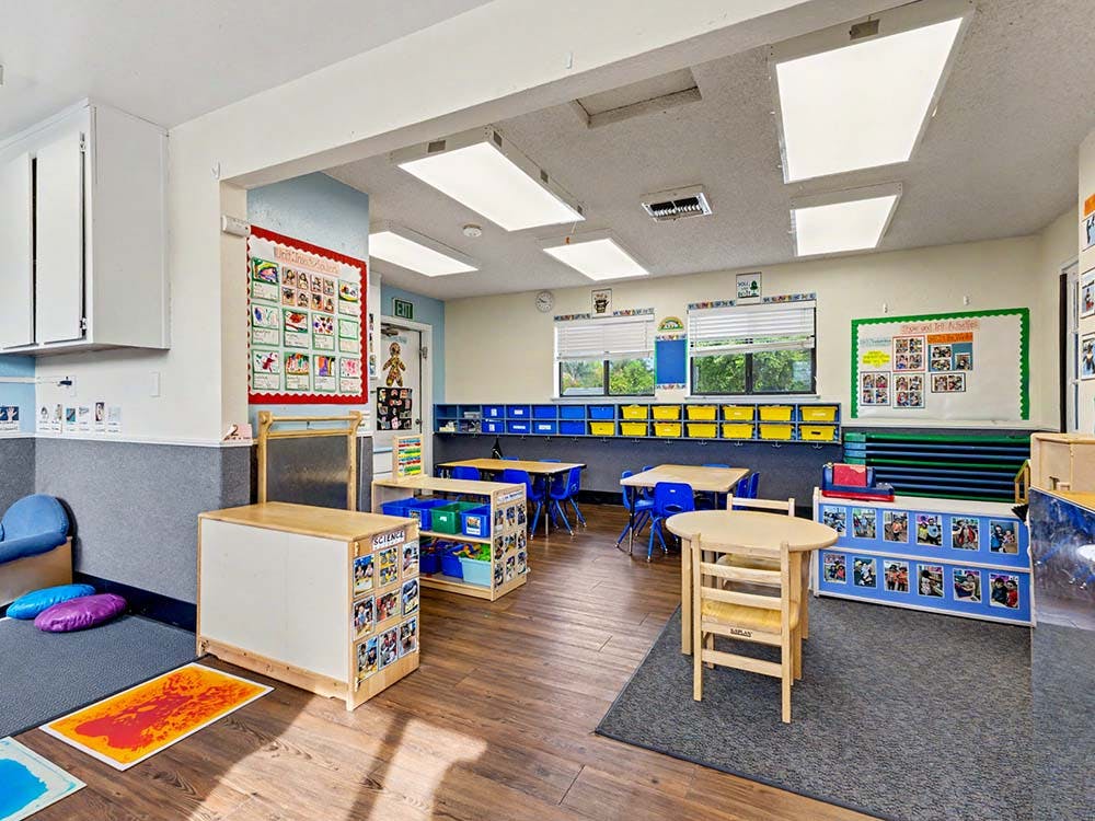 An empty early childhood classroom with small tables and chairs