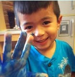 Child with blue paint on hand holding up two fingers