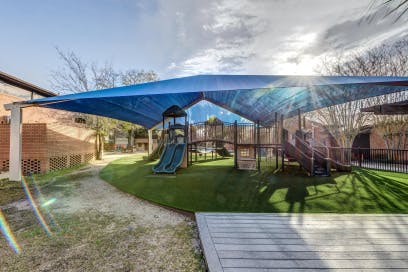 Playground with slides and climbing structures under a blue shade canopy