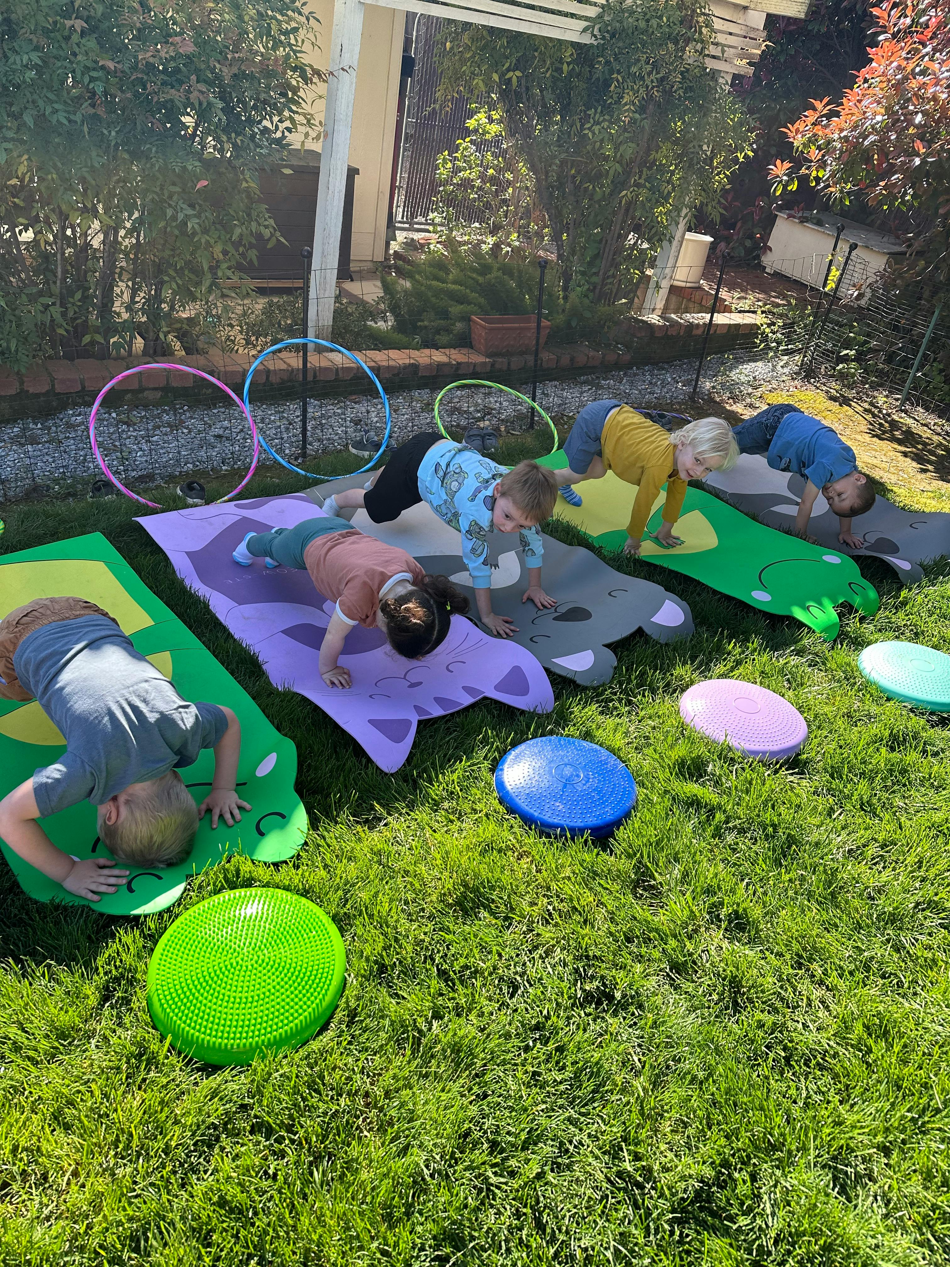 Children doing push-ups on yoga mats outdoors