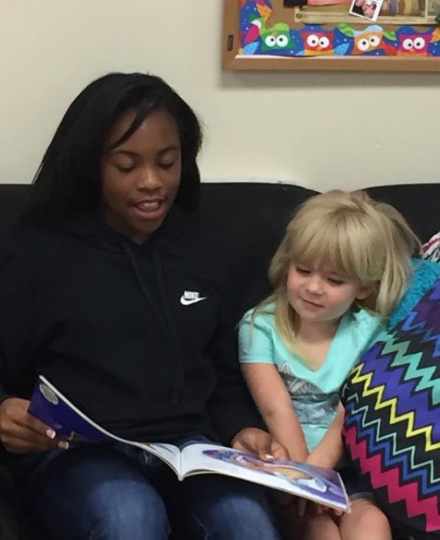 Teen and child reading a book together