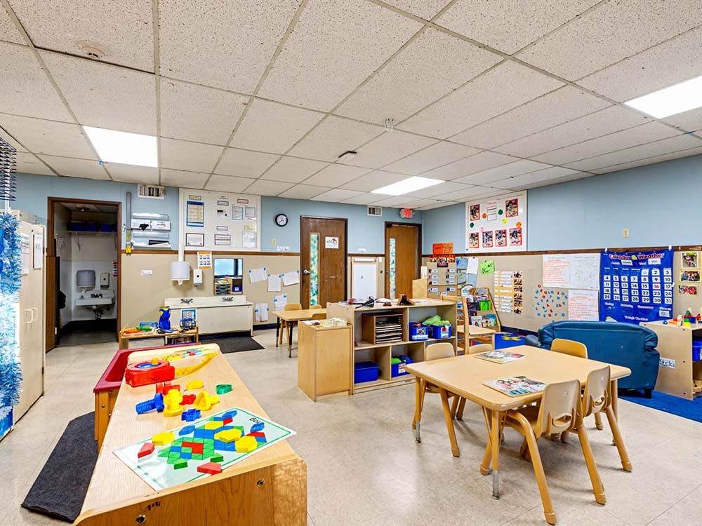 Empty colorful preschool classroom with small tables and chairs