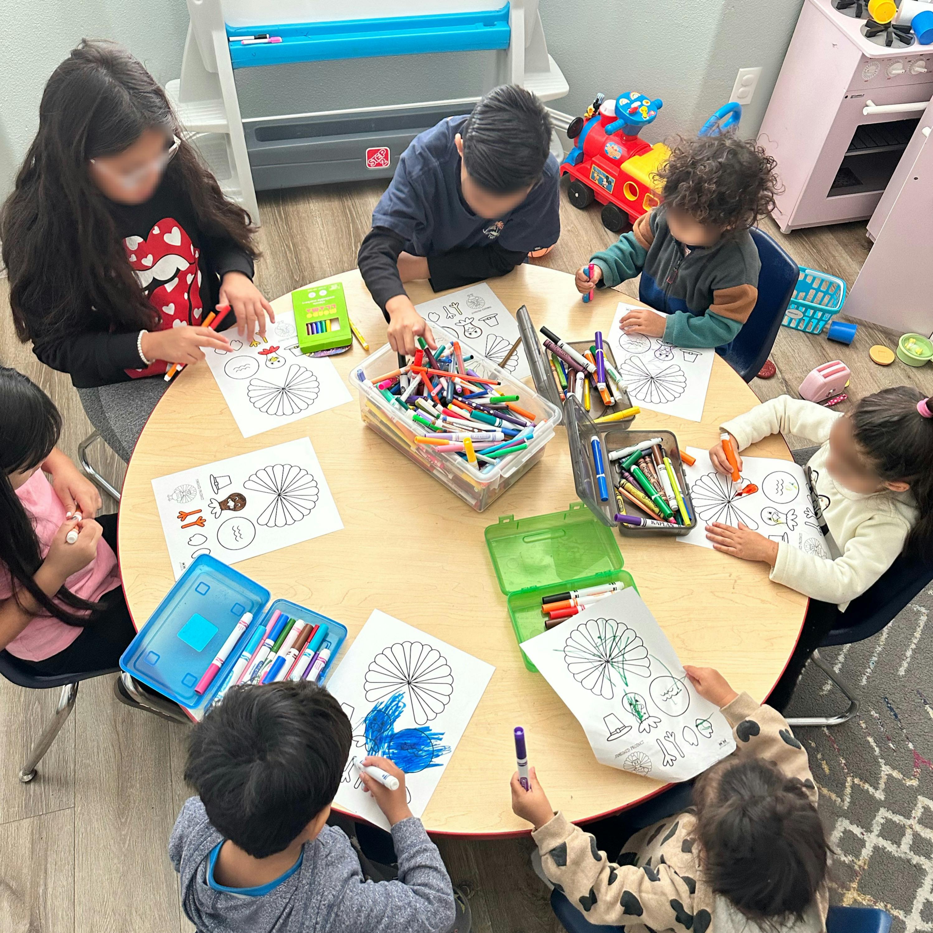 Children coloring at a round table with markers