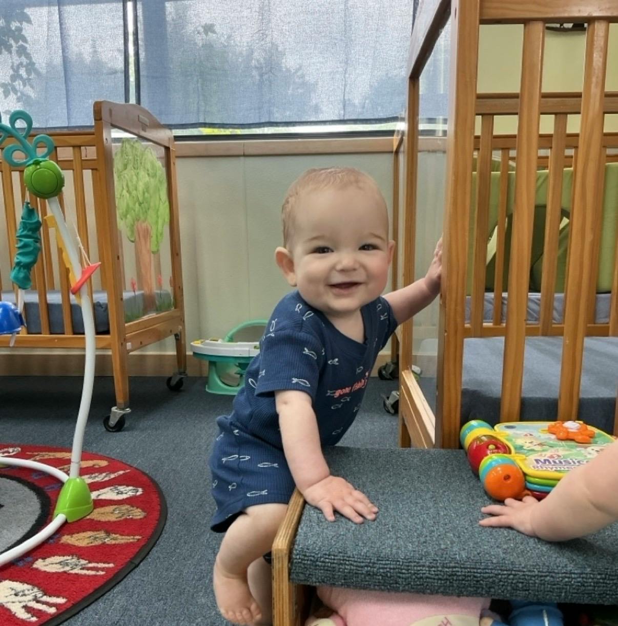 Child standing while holding onto a low shelf in a childcare center