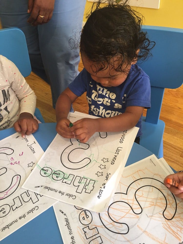 Child coloring a number three worksheet