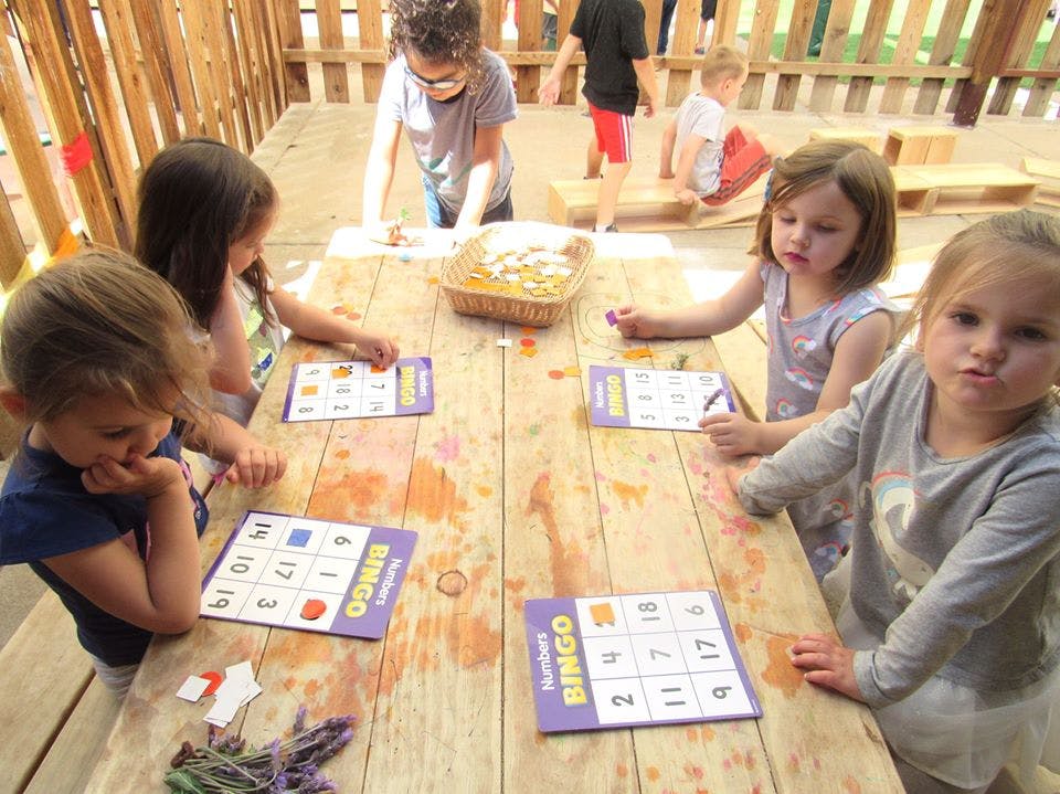 Children playing bingo at a wooden table