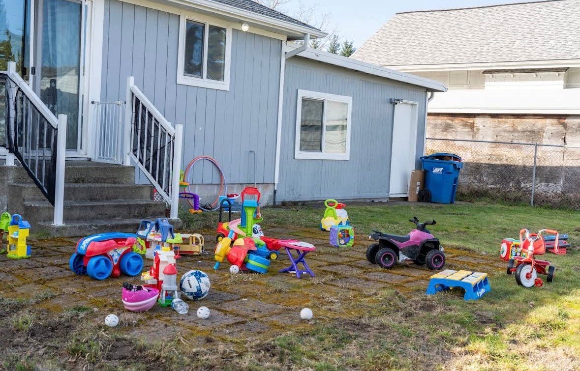 Children's toys scattered on a grassy backyard patio