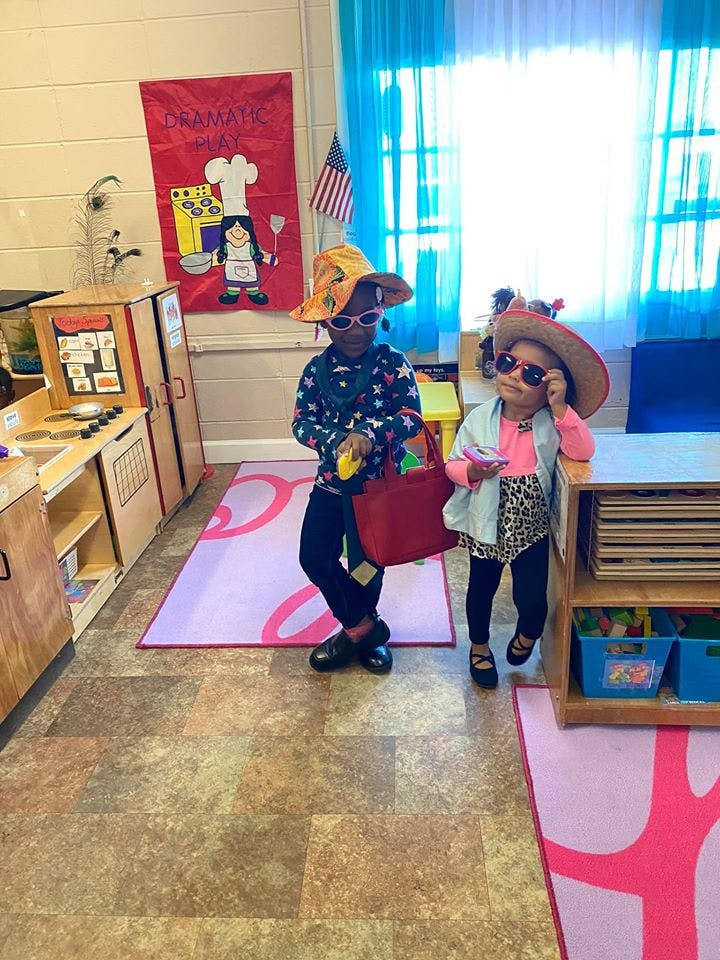 Two children in hats and sunglasses in a classroom