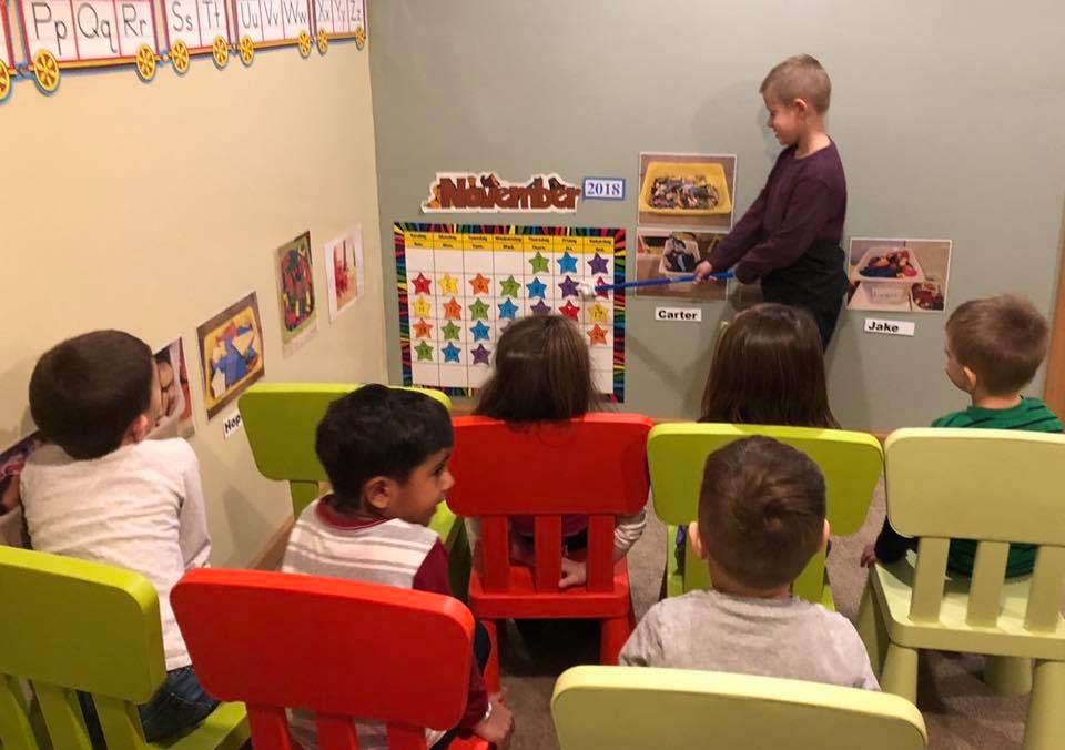 Child standing in front of seated children in a classroom