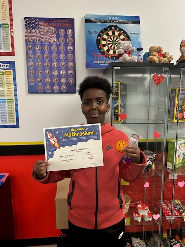 Teen holding a "Welcome to Mathnasium!" certificate and a small basketball