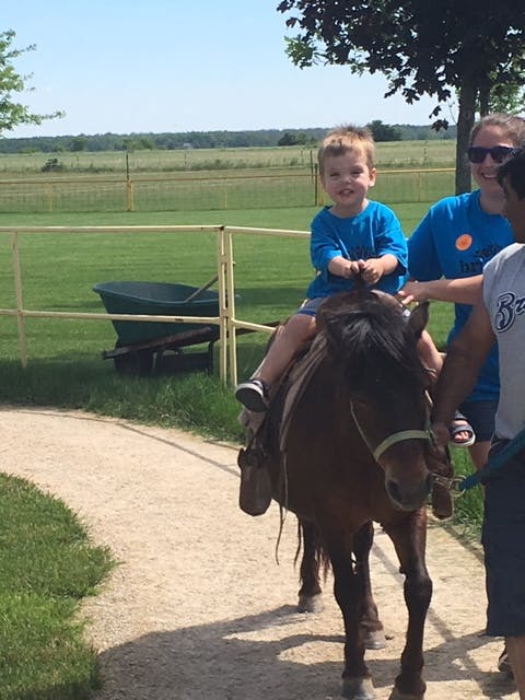 Child riding a pony with people walking alongside