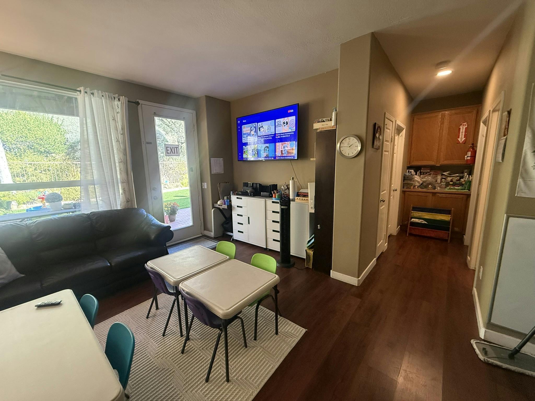 Living room with a large TV on the wall, dark couch, and children's tables