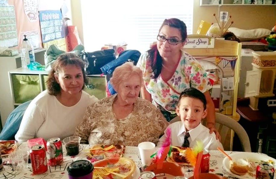 Four people, including a child, sitting at a table with food and drinks