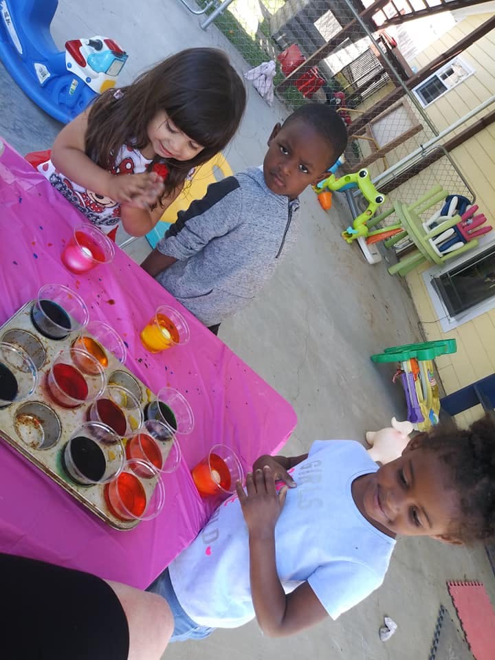 Three children at a table with colorful liquids in cups