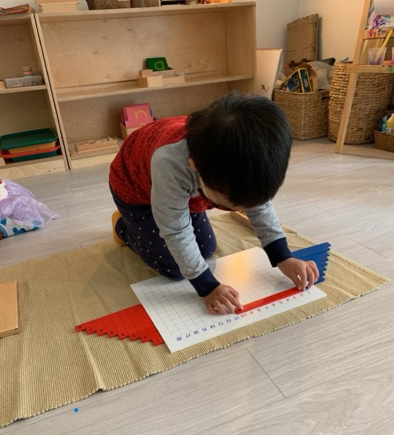 Child kneeling on floor, working with learning materials