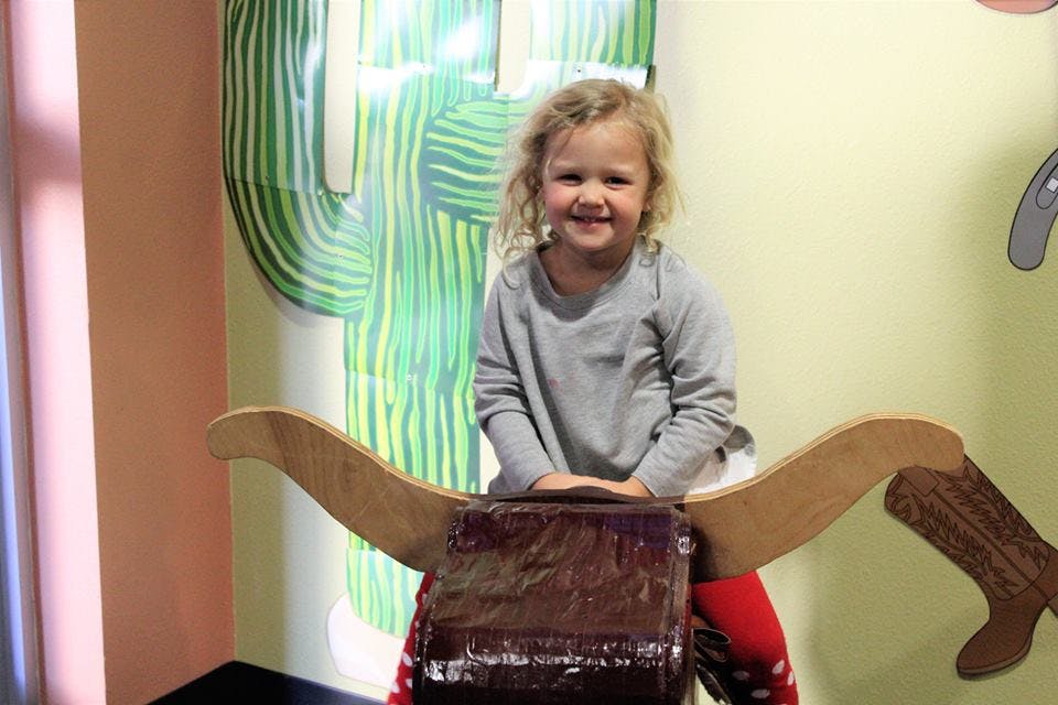 Child sitting on a wooden bull