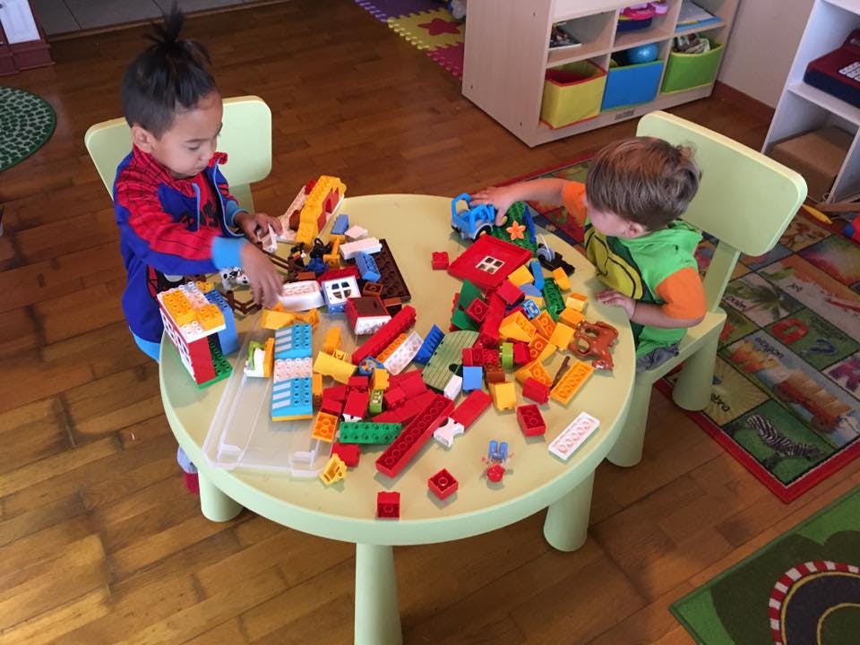 Two children playing with building blocks at a table