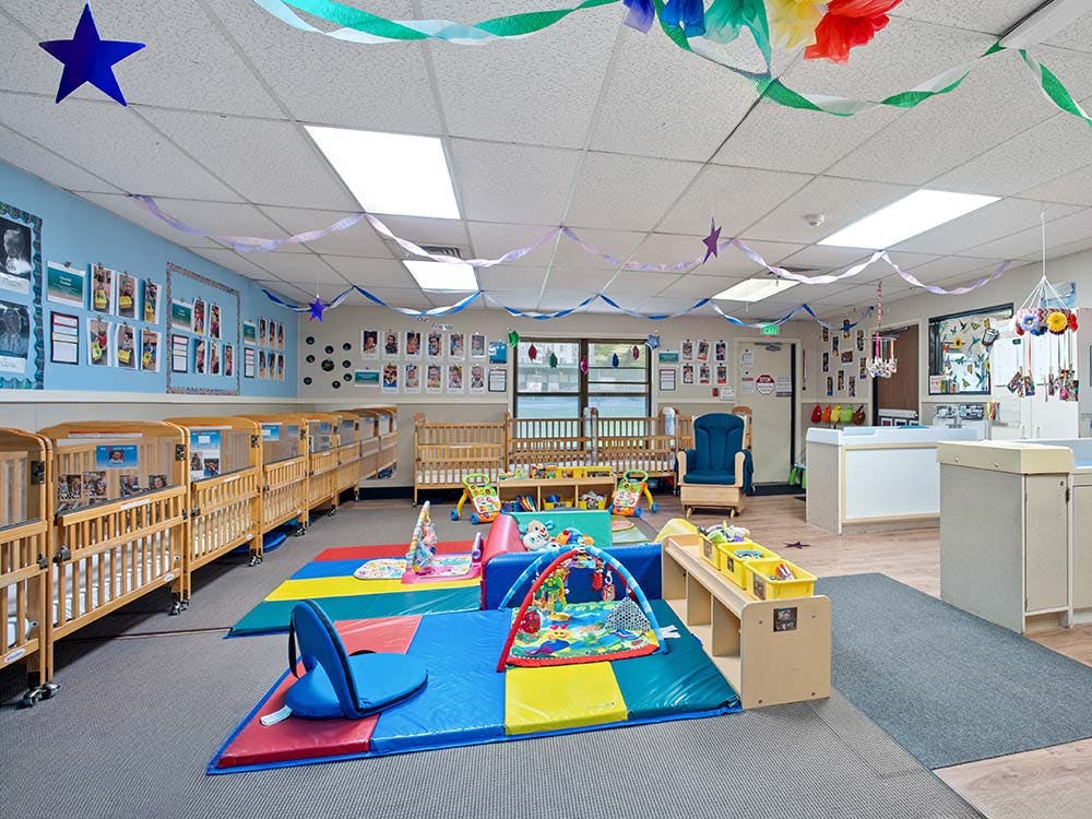 Cribs and play mats in a bright nursery classroom
