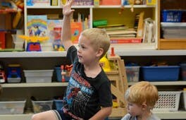 Child raising hand in a classroom